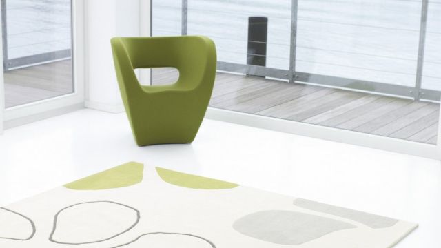Heller Teppich mit organischem Muster und grünem Sessel